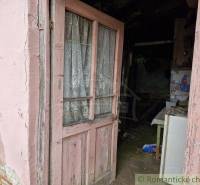 Old wooden door with a lace curtain leading into a neglected interior of a family house.