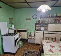 Traditional kitchen in a family house with antique cabinets, oven, and decorations.