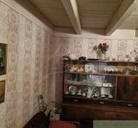 A visible rustic living room in a family house with a display cabinet full of antique glass and porcelain.