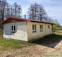 A cottage in nature with a white facade surrounded by grass and trees, an ideal place to relax.