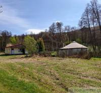 In the photo, there is a cottage in a natural setting with a clear blue sky.