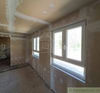 Interior in a cabin with unfinished walls and large windows, waiting to be completed.
