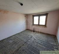 An empty room with a wooden floor, a plastic window, and a family house.