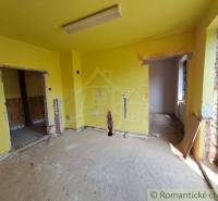 A room in a family house with exposed bricks and yellow walls, awaiting renovation.