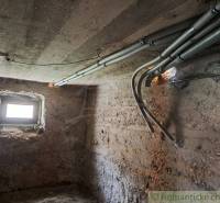 Basement of a family house with a window and electricity; rough plaster, concrete ceiling.