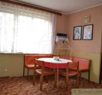 Interior of a family house with a dining nook, armchairs, curtains, pictures on the wall.