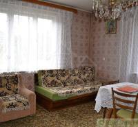 Living room of a family house with tapestry upholstery, crocheted curtains, and wall decorations.