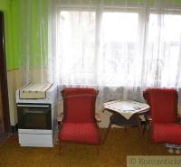 Living room in a family house with red armchairs, a table, and a retro stove.