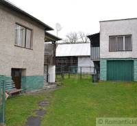 Family house with a garage and yard, buildings, fence, and green lawn.
