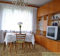 Dining room of a family house with a wooden living room, television, and a lace tablecloth on the table.