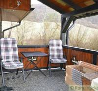 A covered terrace of a family house with two chairs and a table, surrounded by a natural scenery.