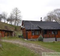 A wooden cottage in nature surrounded by trees and a landscaped garden, family house.