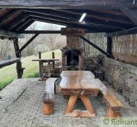 Rustic terrace with a stone oven and wooden seating at a family house in the countryside.