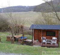 A cottage by the forest hill, equipped with outdoor seating and a wooden terrace for relaxation.