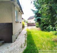 A family house in Košeca surrounded by a garden with greenery and a walkway.