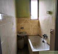 Narrow bathroom with a bathtub and a sink in a family house, typical rural environment.