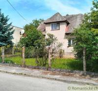 A family house in Košeca surrounded by greenery and a fence on a quiet street.