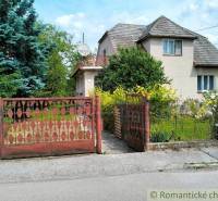 A family house in Košeca with a flower garden and a wooden gate in front of the house.