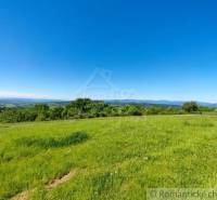 Green meadows and blue skies with a view of the hills create a scenery.