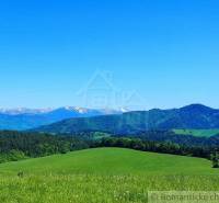 Peaceful landscape, hills, mountains with snow, meadows, trees, blue sky, with gardens.