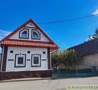 Traditional family house with a wooden roof and typical windows, street, fence, sky.