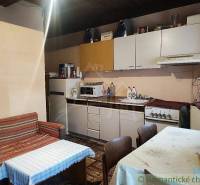 A kitchen in a family house with a kitchen unit, refrigerator, sofa, and table.