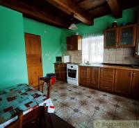 The interior of a cottage with green walls, a kitchen, and wooden furniture, ideal for a family home.