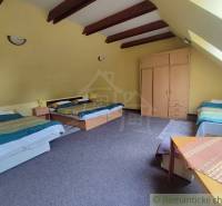 An attic room in a family house with beds, a wardrobe, and a window in the slanted ceiling.