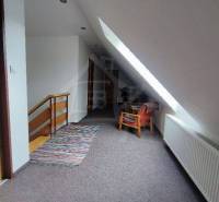 Attic hallway in a family house with a staircase, chair, and radiator.