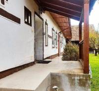 Traditional house with a wooden roof and entrance, view of the yard with a lawn.