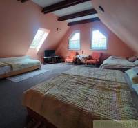 The attic bedroom offers three beds, a television, and a seating area, suitable for a family house.