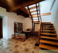 The interior shows a rustic stove, wooden stairs, and paneling in a family house.