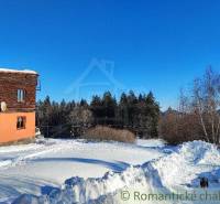 A snowy plot with a cottage surrounded by nature and a view of the forest: family house.