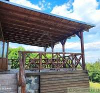A wooden terrace, attached to a family house, with a view of nature and the forest.