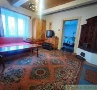 Living room with a tiled stove, wooden furniture, carpet, and television in a family house.