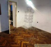 A room with a parquet floor, doors, a fireplace stove, and a mirror within a family house.