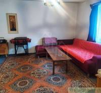 Living room with an old carpet, sofa, table in a family house, decorated with a painting and a curtain.