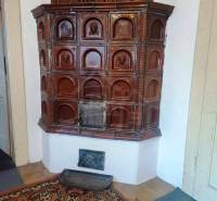 Traditional tiled stove on a red carpet in the living room of a family house.