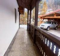 Entrance with a porch and adjacent parking at a family house in a mountain setting.
