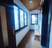 A narrow interior with a wooden ceiling, tiles, and a bench in a family house.