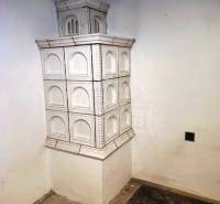 A white tiled stove in the corner of a family house with a wooden floor.