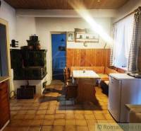 Country kitchen with a tiled stove, wooden paneling, and a corner bench for a family house.