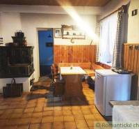A country kitchen with a stove, wooden furniture, and a tiled stove in a family house.