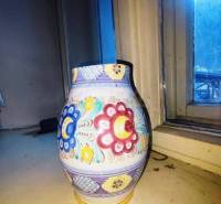 A colorful ceramic vase with floral patterns on the windowsill of a family house.