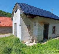 A small family house with a garden, grass, and surroundings in a mountainous landscape.