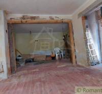 Room under renovation, described Family house with a chair, ladder, bucket, and a large wall.