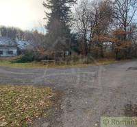 A path in front of an abandoned family house, surrounded by trees near a forest in autumn colors.