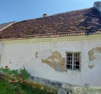 An old family house with a tiled roof, surrounded by nature and a lawn.