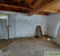 An old interior of a country cottage with ceiling beams and worn walls.