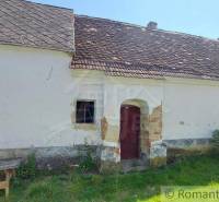 Old family house with peeling plaster, wooden table next to the house.
